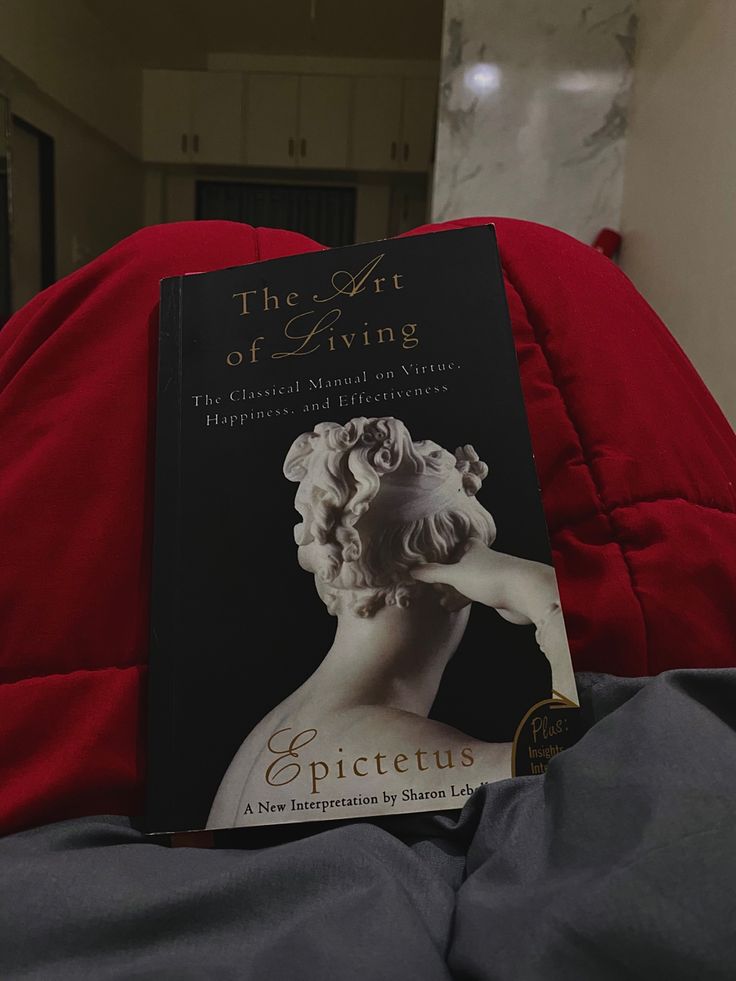 a book sitting on top of a bed next to a red pillow in a room