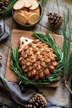 a wooden table topped with pine cones and crackers next to a bowl of cookies