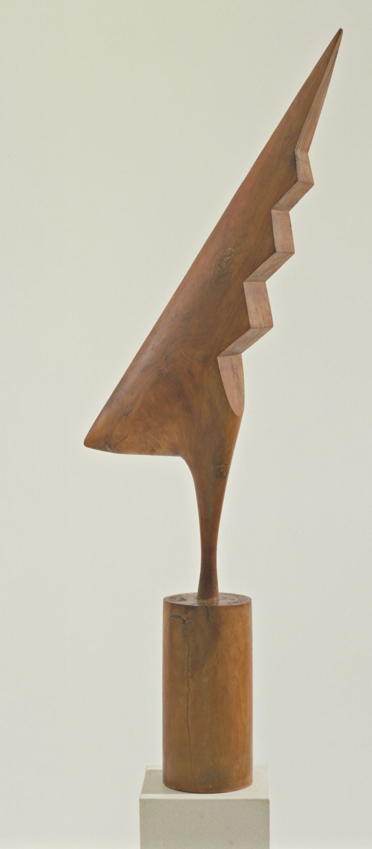 a wooden sculpture sitting on top of a white pedestal