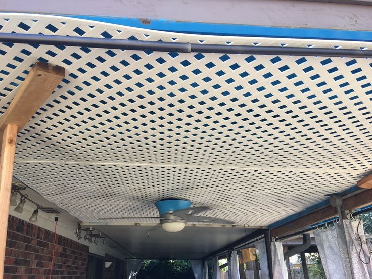 an outdoor covered patio area with blue and white tiles on the ceiling, along side a brick building