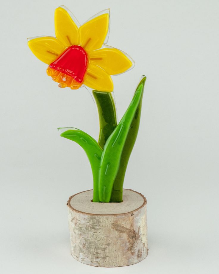 a yellow and red flower sitting on top of a wooden stump