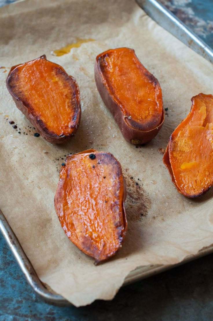 four cooked sweet potatoes on a baking sheet