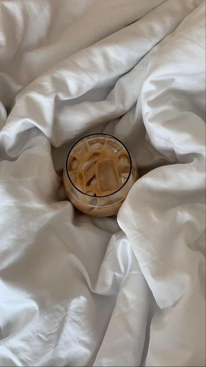 a bowl with noodles in it sitting on top of a white bed sheeted surface