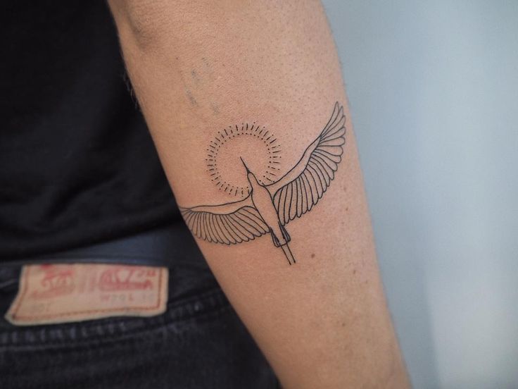 a small tattoo on the arm of a woman with a bird in it's wings