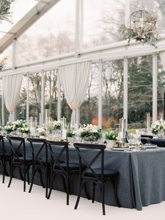 a long table is set up with black chairs and white flowers in vases on the tables