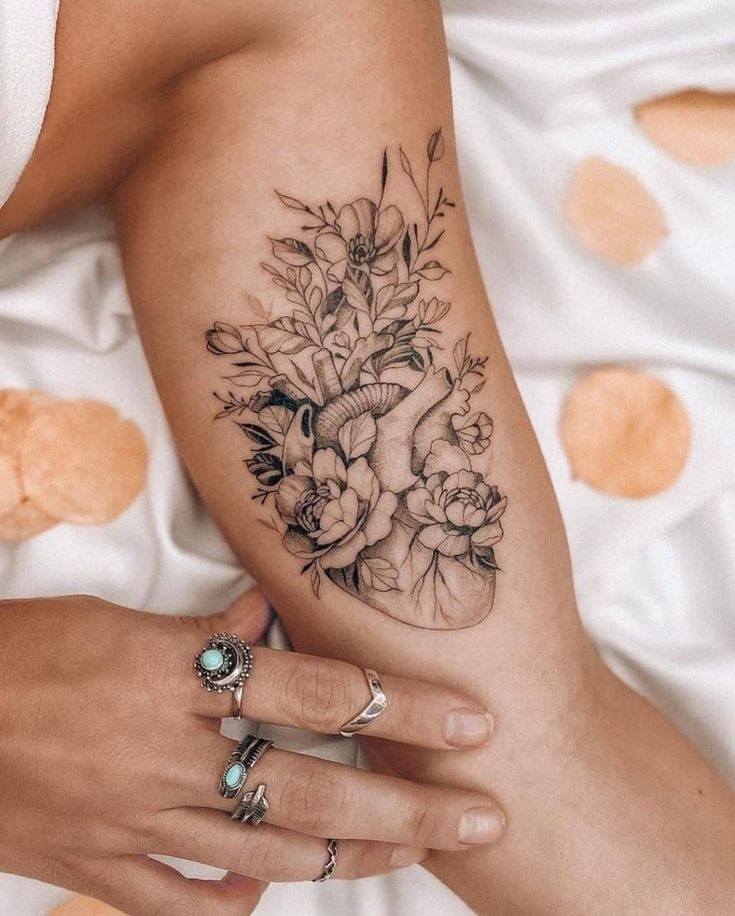 a woman's arm with flowers on it and a ring in the middle of her hand