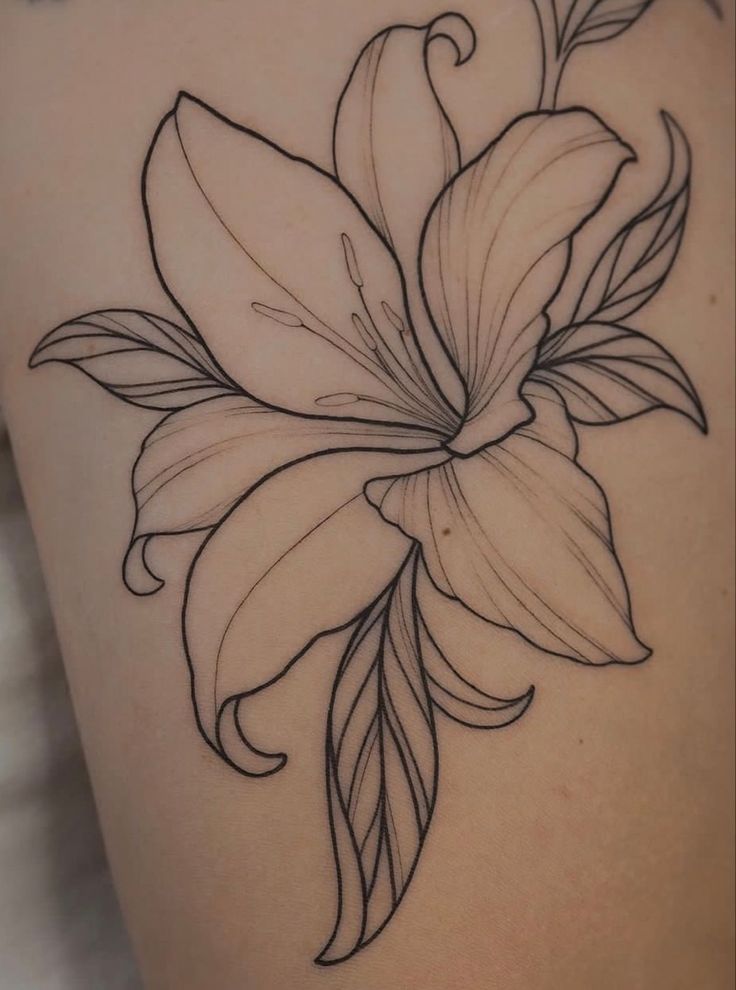 a black and white photo of a flower on the back of a woman's thigh