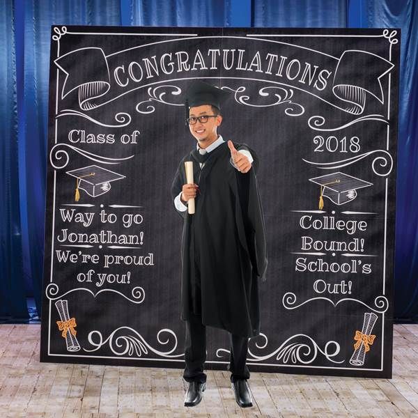 a man in graduation gown standing next to a blackboard with congratulations written on it