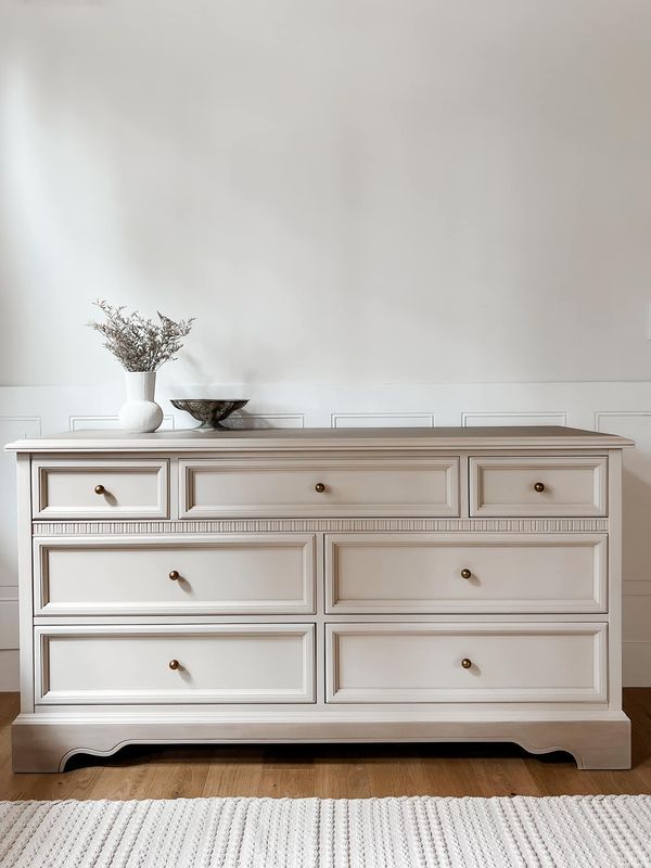 a white dresser with two vases on top of it and a rug in front of it