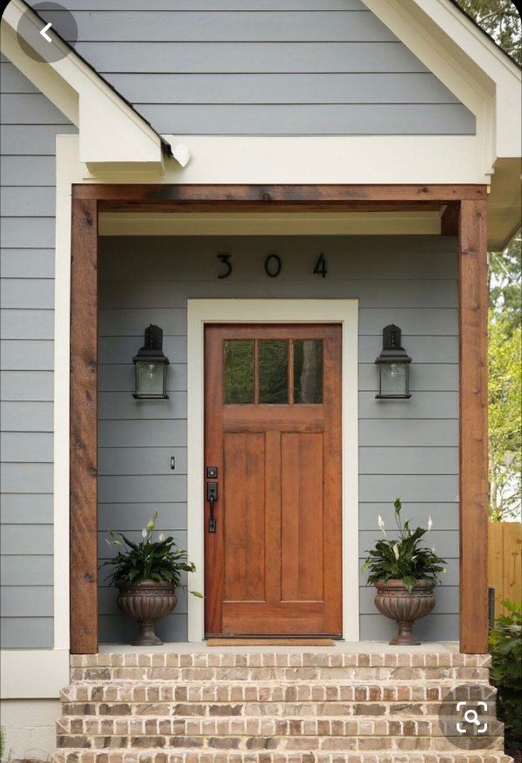 a front door with two planters on the steps