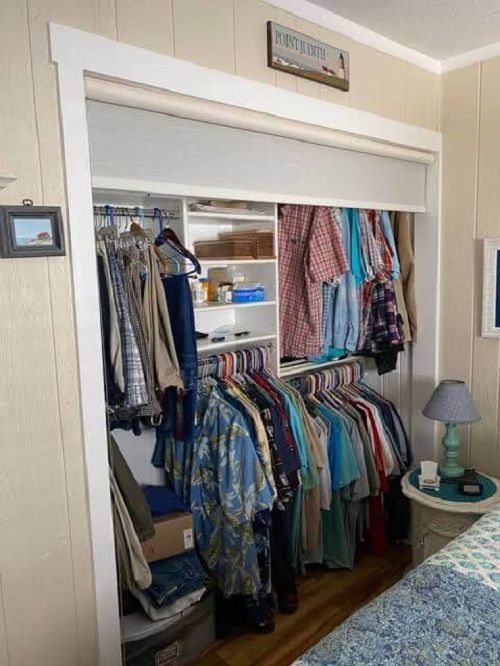 a bedroom with a bed, closet and clothes hanging on the wall in front of it