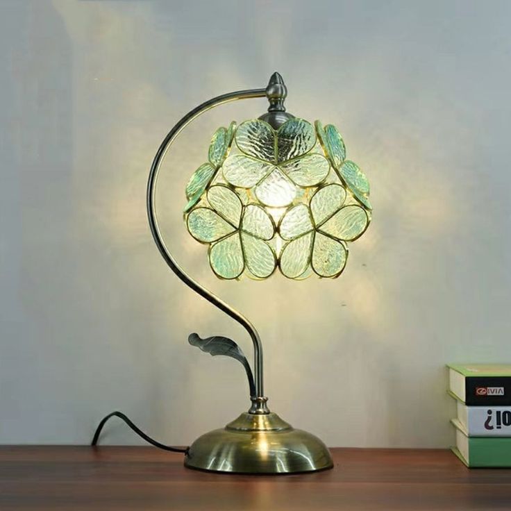 a table lamp sitting on top of a wooden desk next to a box and book