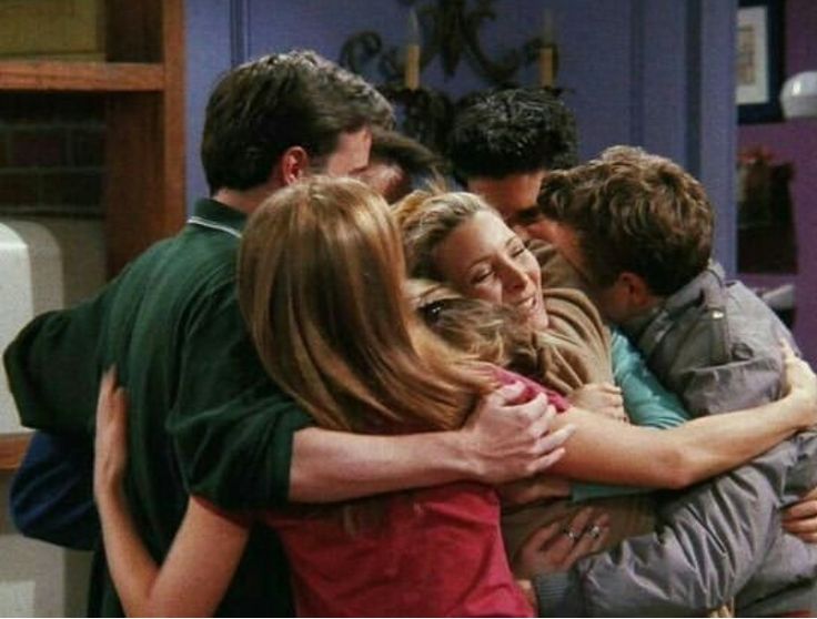 a group of people hugging each other in a kitchen