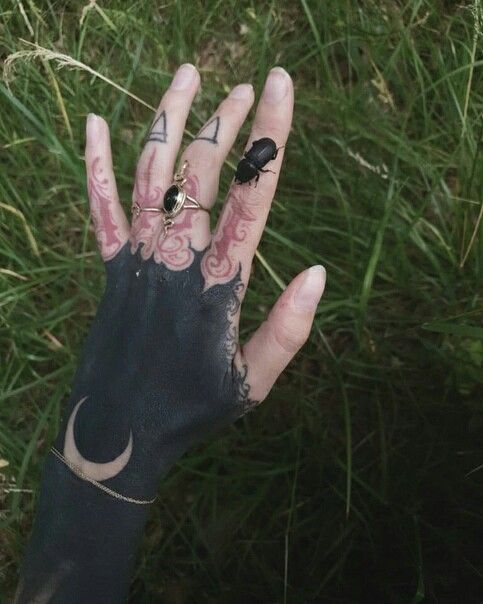 a person's hand with tattoos on it and a ring in their left hand