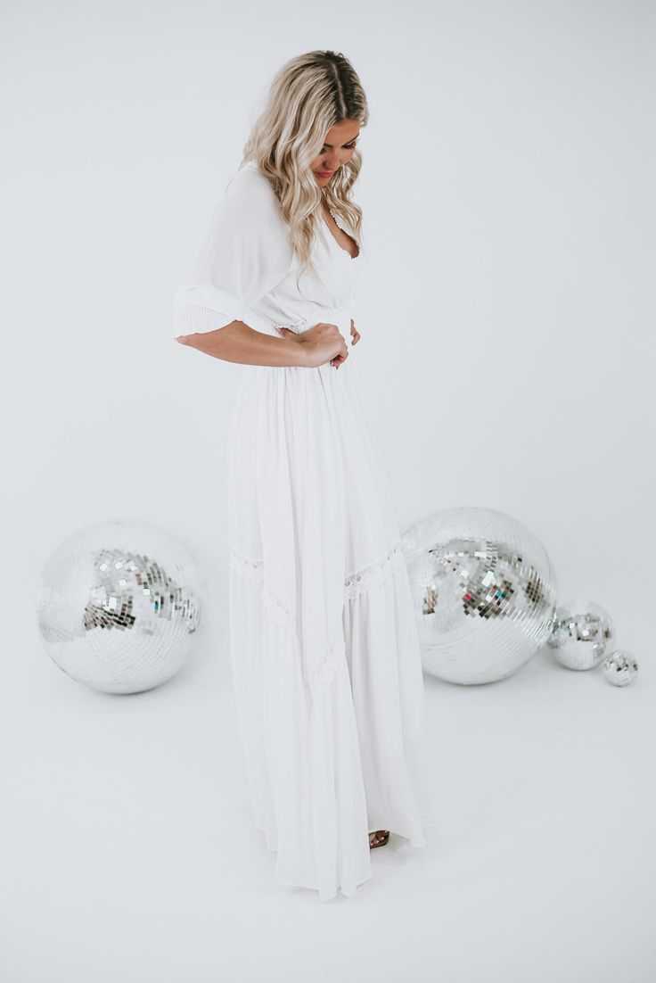 Instantly become the most adored, this stunning maxi features a cinched waistline, cuffed mid-length sleeves, full lining, and intricate lace detailing throughout. The most whimsical piece for all seasonal occasions! Neckline: Lace V Fabric: 100% polyester; Lining: 100% Polyester Details: Cinched waistline, lined, mid-length cuffed sleeve, lace detailing, adjustable tie back Fit: True to size, if in between sizes we recommend sizing down! - Arms: Relaxed; Mid-length cinched sleeve- Chest: Relaxe White Flowy V-neck Maxi Dress, White Fitted V-neck Maxi Dress, Chic V-neck Dress For Beach Wedding, White V-neck Fitted Maxi Dress, Chic Solid Color Wedding Dress, Chic V-neck Beach Wedding Dress, Chic White Maxi Dress For Wedding, White V-neck Midi Dress For Wedding, White Formal Maxi Dress For Summer