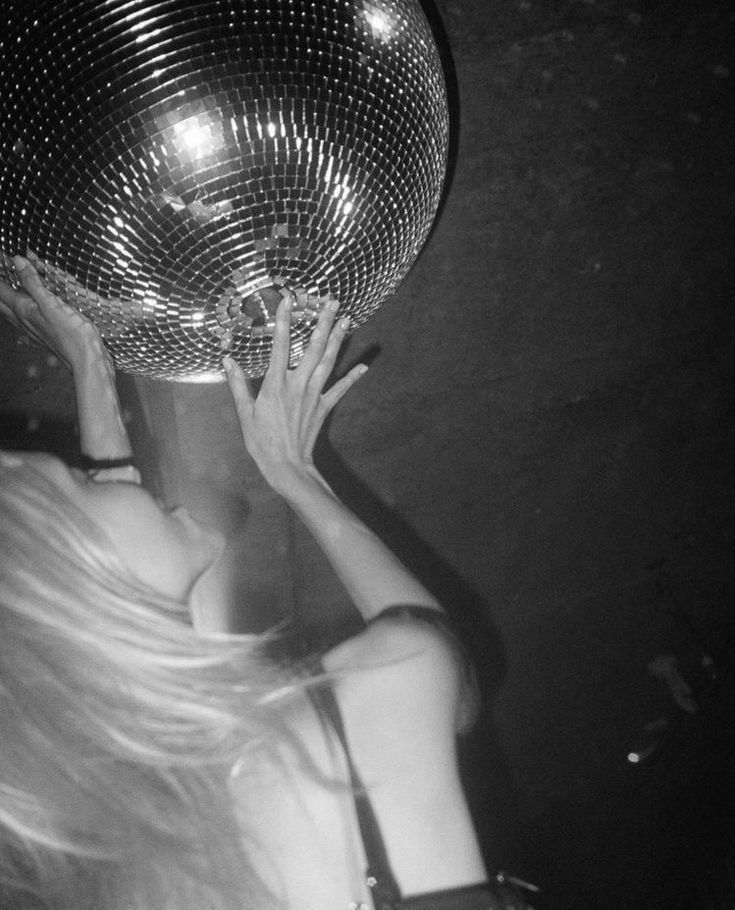 a woman holding up a disco ball in front of her face