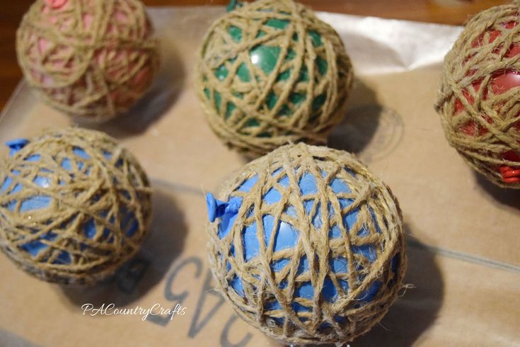 four balls are wrapped in twine and sitting on a piece of cardboard