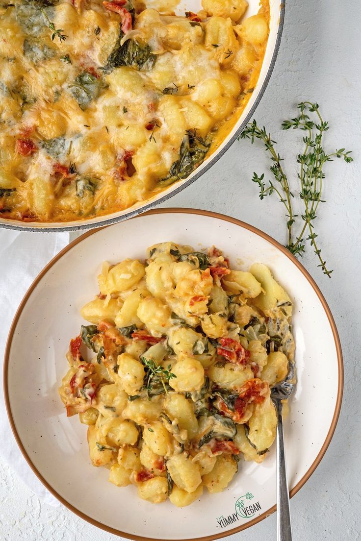 two plates filled with macaroni and cheese on top of a white tablecloth