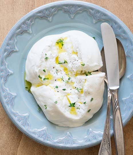 a blue plate topped with whipped cream next to a fork and knife on top of a wooden table