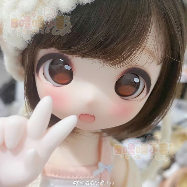 a close up of a doll wearing a dress and holding her finger to her nose