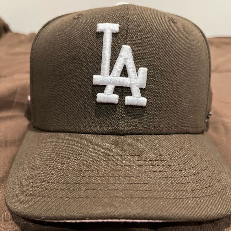 a baseball cap with the los angeles dodgers on it sitting on top of a bed