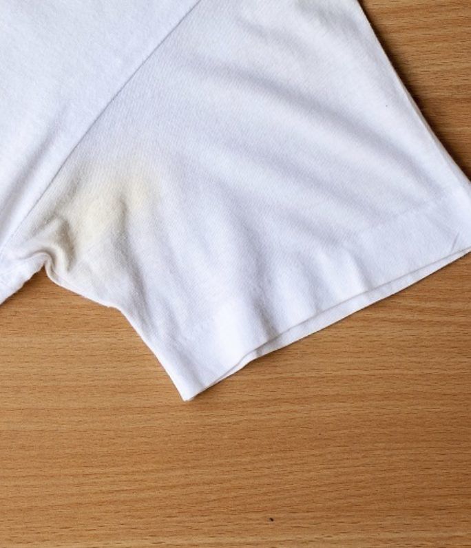 two white t - shirts sitting on top of a wooden table