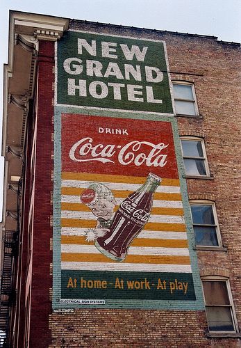 an advertisement on the side of a building advertising new grand hotel drink coca - cola