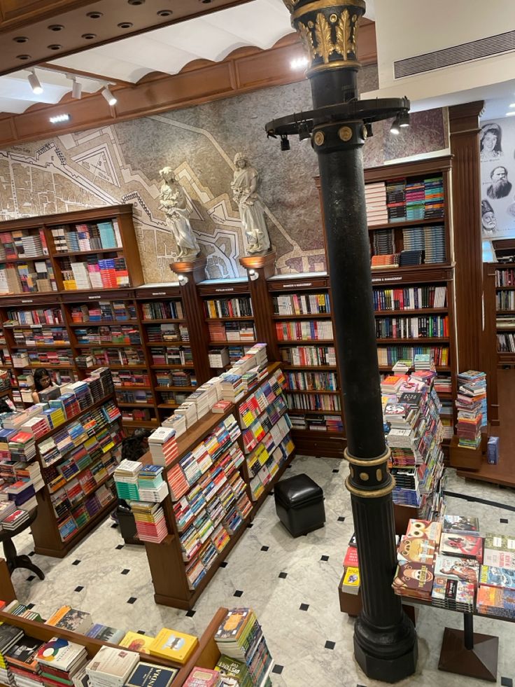 the inside of a bookstore with many books on shelves and a lamp post in the center