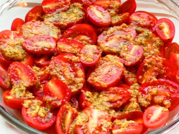 a glass bowl filled with sliced tomatoes and meat toppings on top of a table