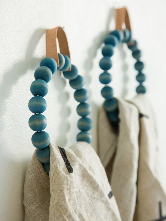 two bags are hanging on the wall with some beads attached to them and one bag is holding something in it