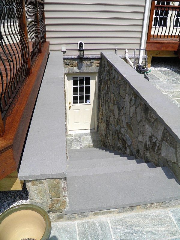 a stone wall with a door in the middle and steps leading up to an entrance