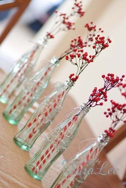 four glass vases with red berries in them