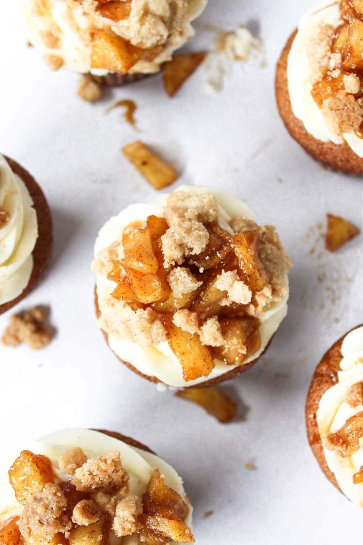 several cupcakes with white frosting and toppings