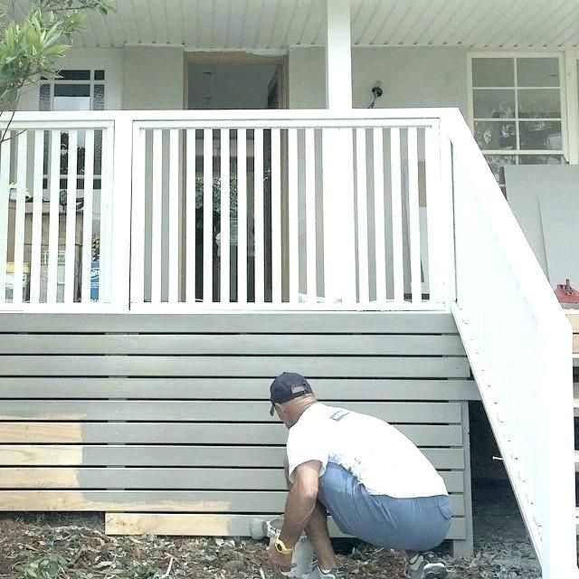 a man kneeling down next to a white house