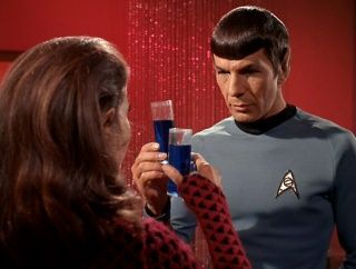 a man in a star trek uniform is holding a glass and talking to a woman