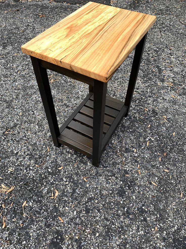 a wooden table sitting on top of a gravel ground