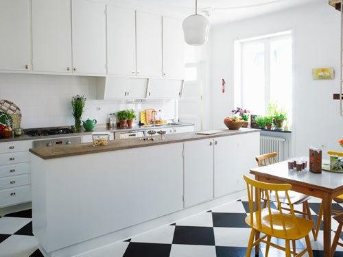 a kitchen with black and white checkered flooring, yellow chairs and wooden table