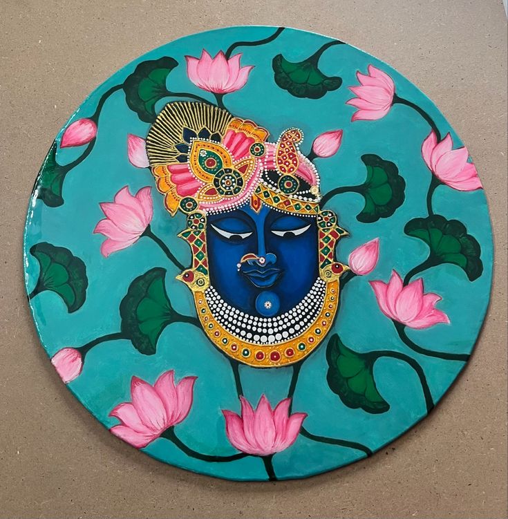 a decorative blue plate with pink flowers and a face painted on the front in bright colors