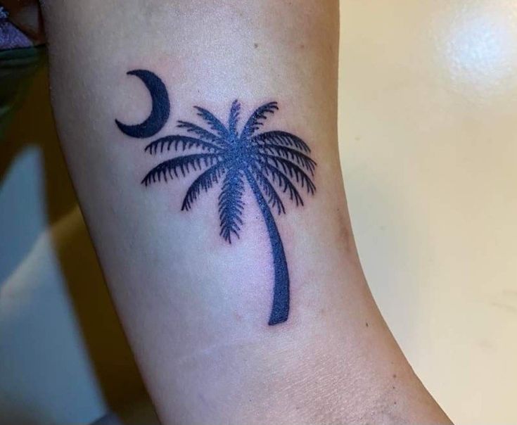 a palm tree and moon tattoo on the arm