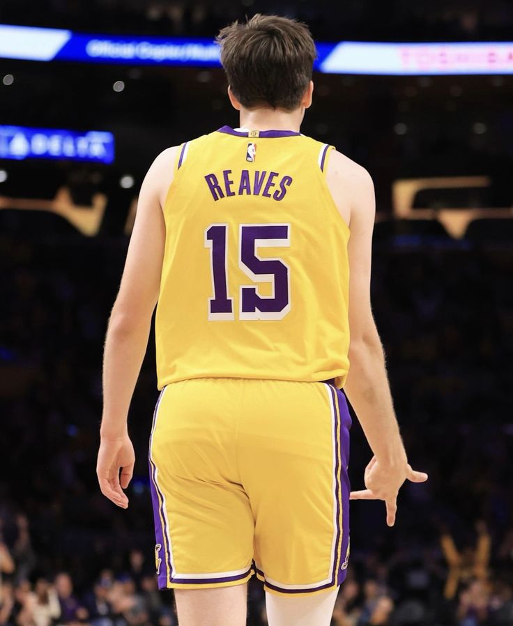 a young man in a lakers uniform standing on the court