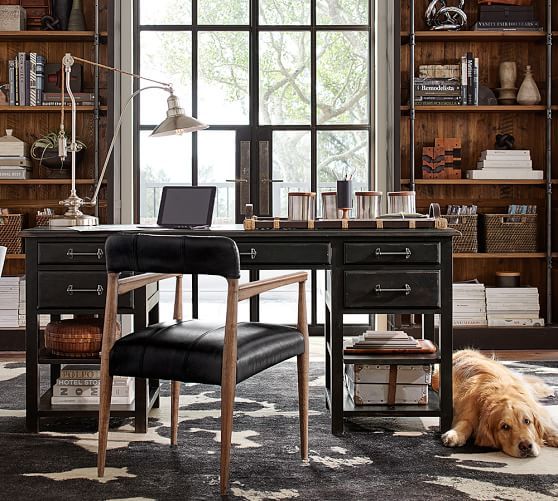 a dog laying on the floor in front of a desk