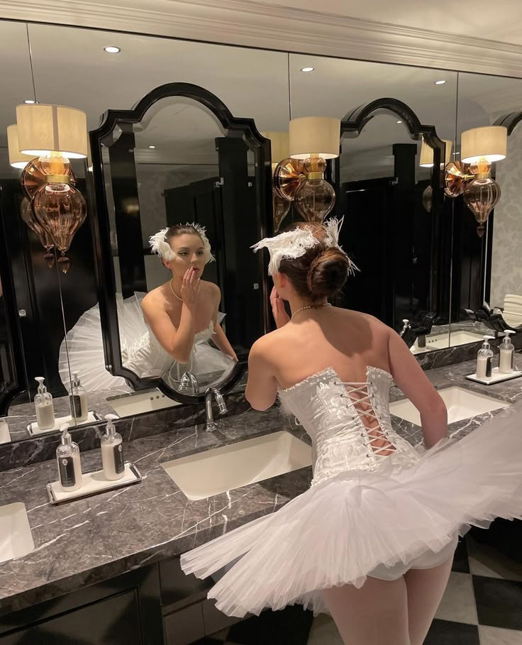 a woman in a white dress standing in front of a mirror