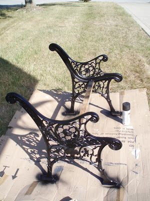 two metal park benches sitting on top of a wooden pallet next to a sidewalk