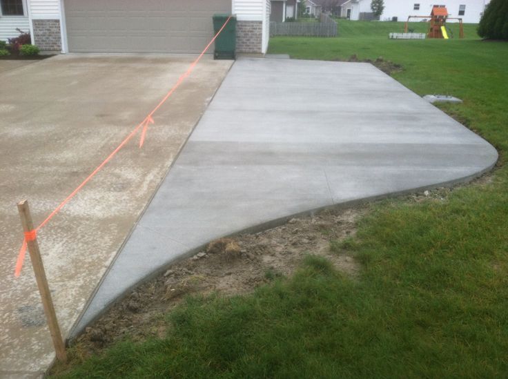 a concrete driveway is being constructed in front of a house with an orange tape on it