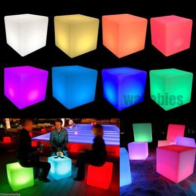 several different colored cubes with people sitting around them on the floor and in the background