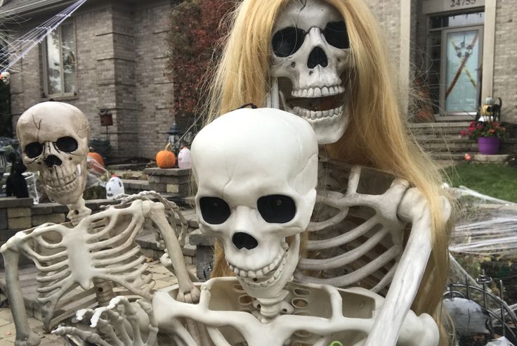 two skeleton statues in front of a house with halloween decorations on the outside and inside