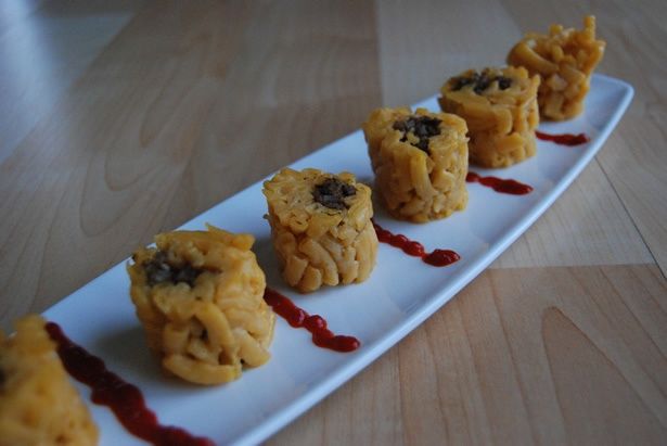 small desserts are lined up on a long white plate with sauce drizzled around them