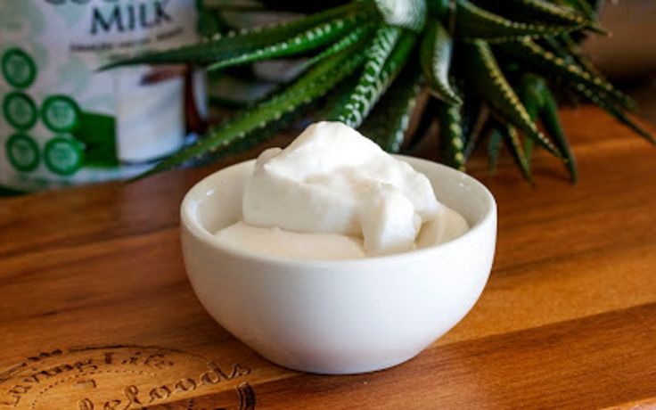 a white bowl filled with whipped cream sitting on top of a wooden cutting board next to a bottle of milk