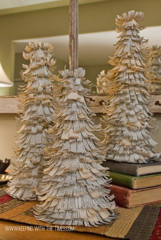 three wooden christmas trees sitting on top of a table next to a lamp and books