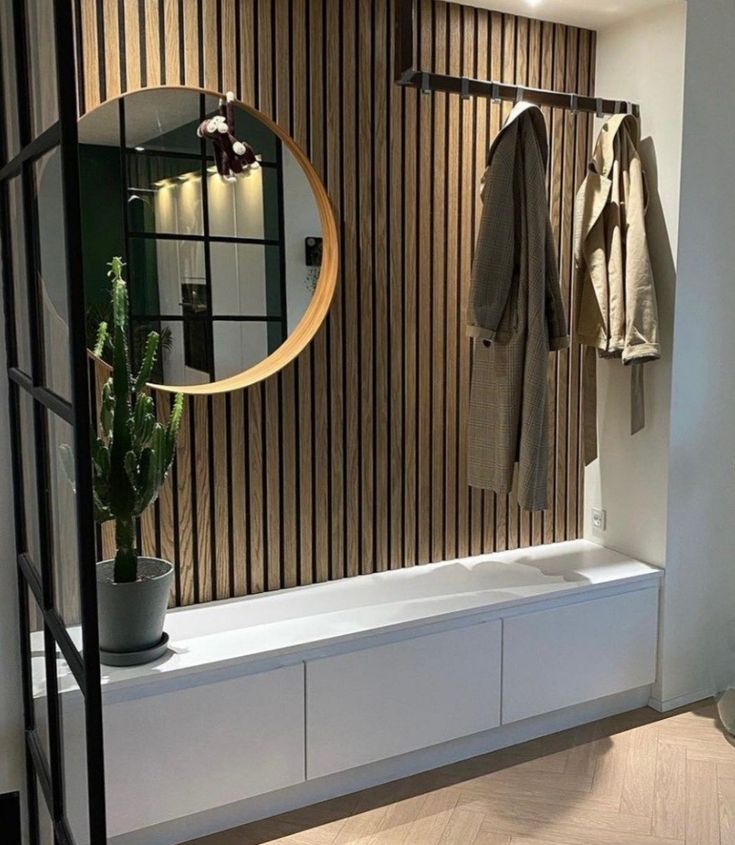 a coat rack with two coats hanging on it and a potted plant in the foreground